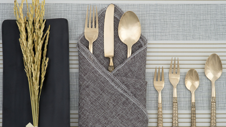 Bronze flatware on grey tablecloth in dark grey napkin