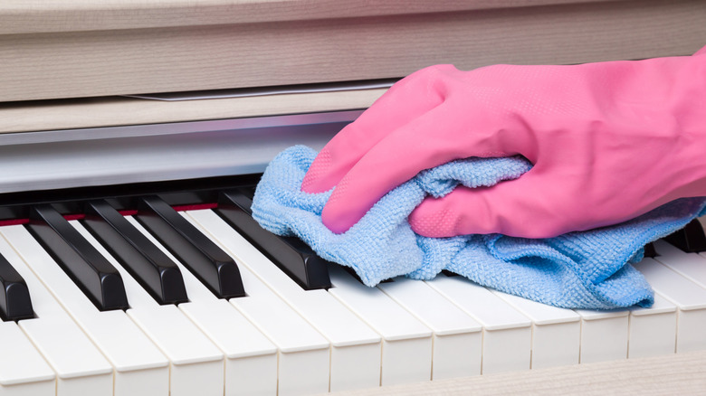 A person cleans piano keys with a cloth