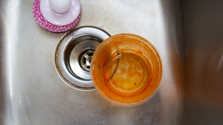 Stained plastic food container in sink