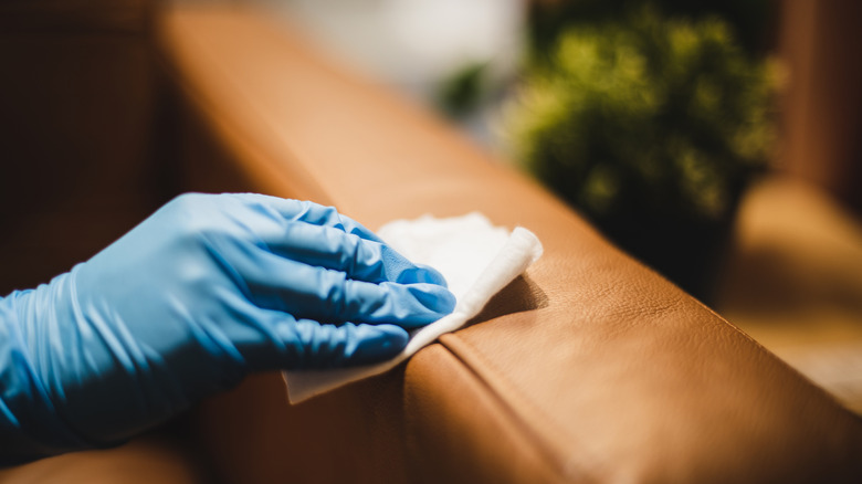 Person wiping cloth on leather couch