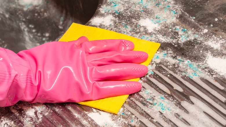 Person wearing pink glove scrubbing soap scum from counter
