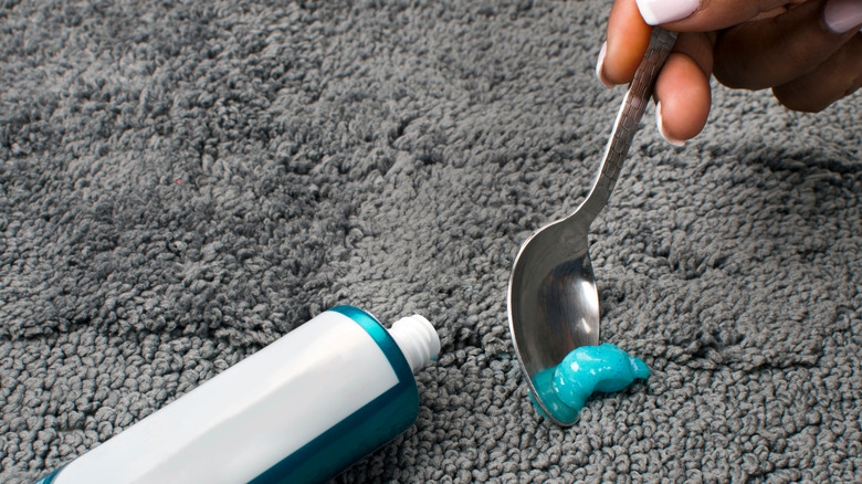 A person cleans a carpet with toothpaste