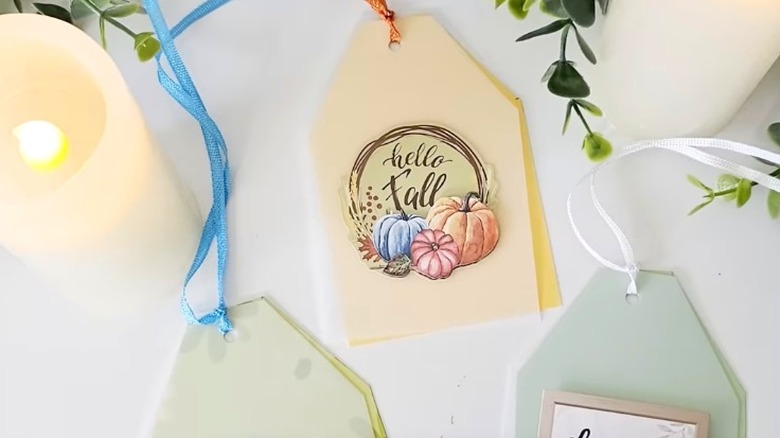 Fall-themed tags lying on table with candles and greenery