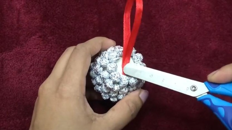 Person making a Christmas ornament out of aluminum foil