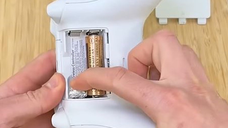 Man using aluminum foil to fix battery in controller