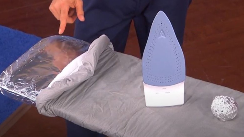 Man showing ironing board with aluminum foil trick