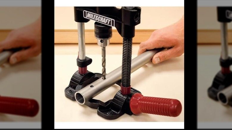 Person using a Milescraft angle drill guide to drill holes in a pipe