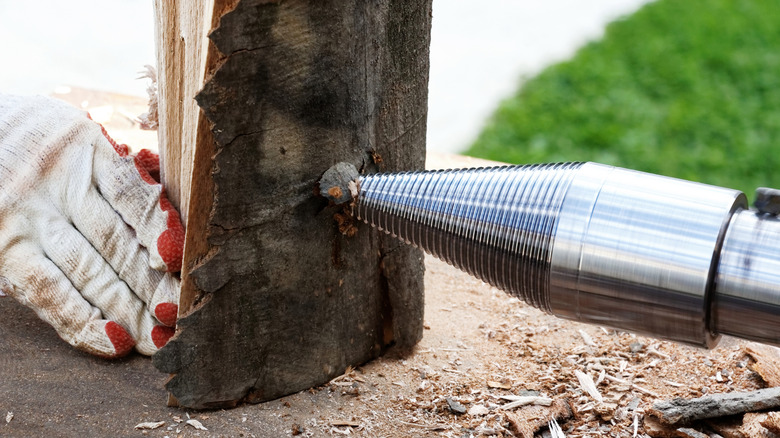 Cone-shaped wood splitter drill attachment being used on a log