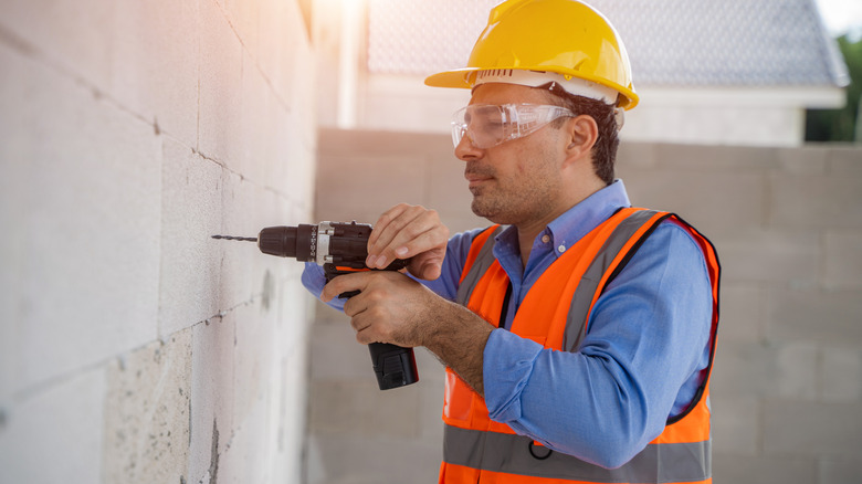 Person drilling into a concrete wall with a special drill bit