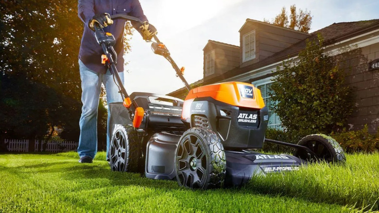 Someone mowing the lawn with an orange ATLAS lawn mower.