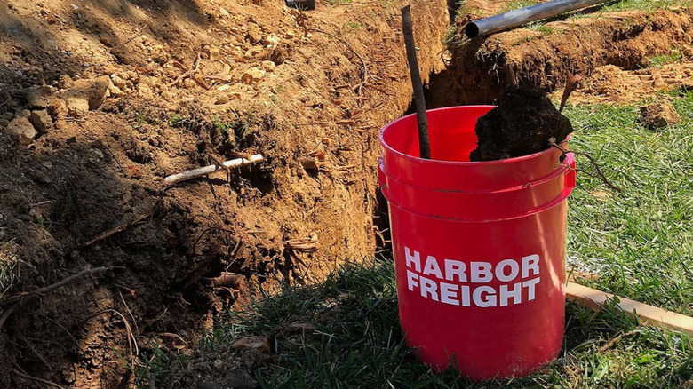 A red bucket next to a pile of dirt.