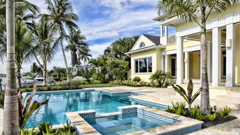 Palm trees around a pool behind a home.