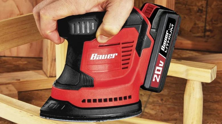 A person using a hand sander made by Bauer