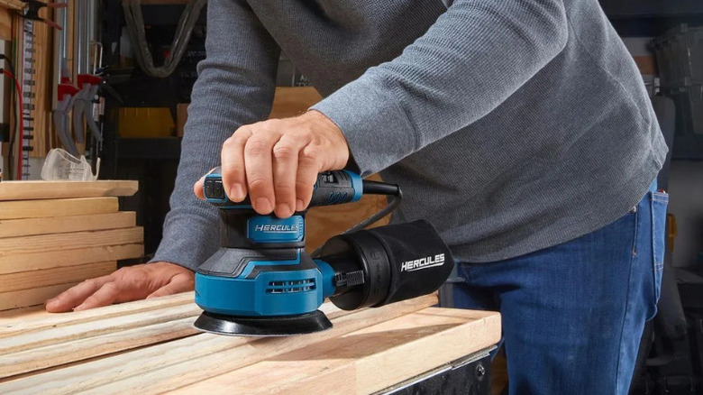 A person using a hand sander made by Hercules