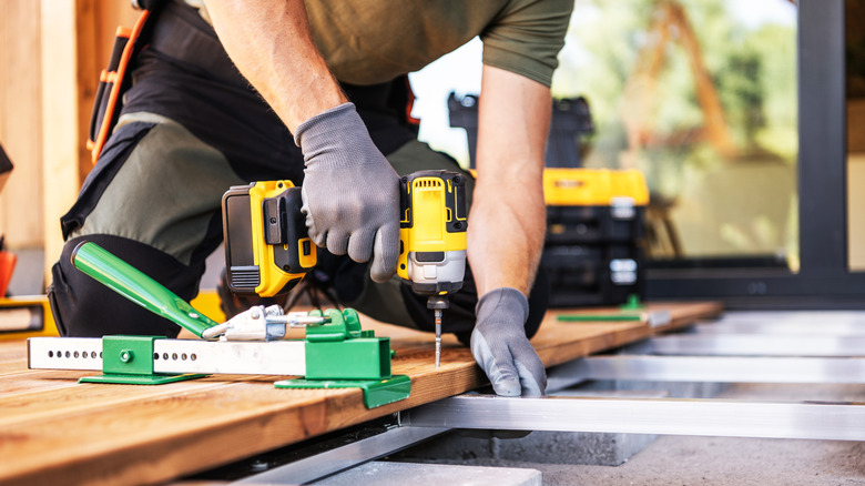 Close-up of a man drilling floorboards with a power tool