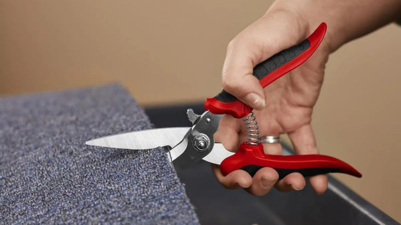 A person using Pittsburgh's multipurpose, 8-inch, stainless steel scissors