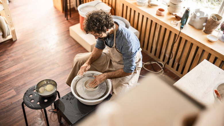 Man sitting at a pottery wheel starting to create a vessel