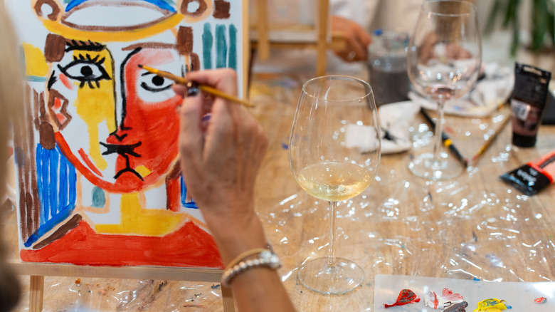 Person paints an abstract face on a canvas that's propped on an easel