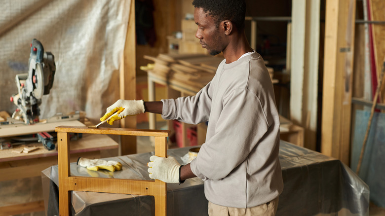 Man staining a wood piece in a workshop area