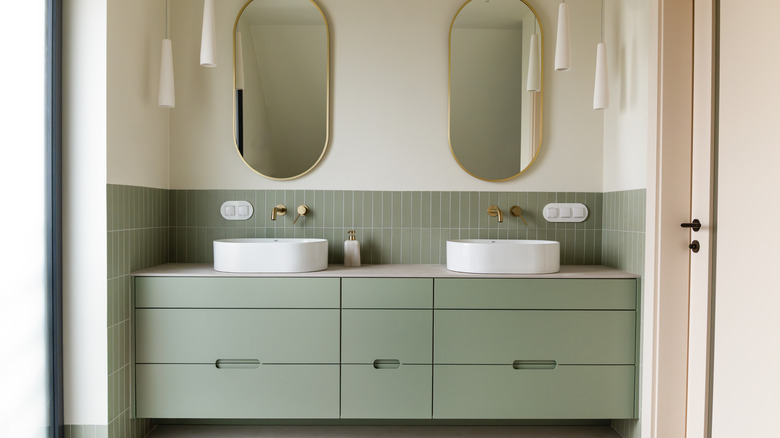 Sage green bathroom counter and half-tiled wall