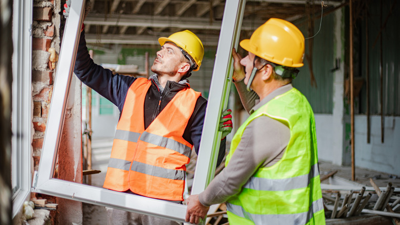 Workers put a new window into a house