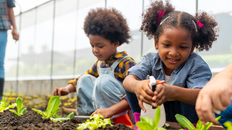 Two young children watering plants