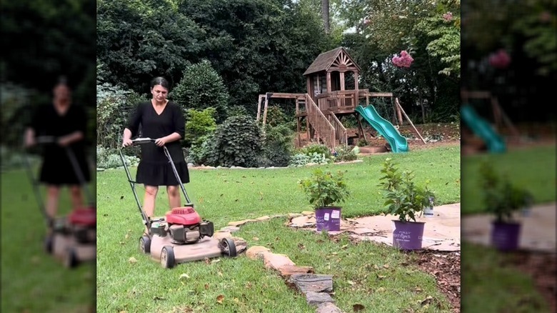 Woman mowing lawn near landscape rocks