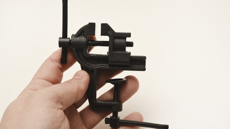 Hand holding a small metal vise