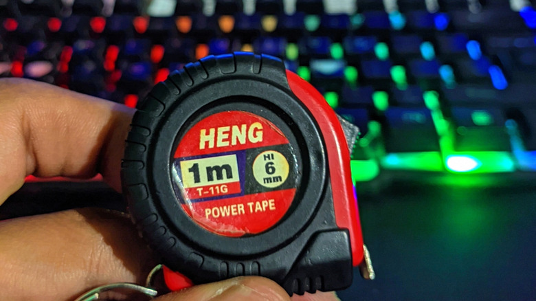 Hand holding a miniature tape measure