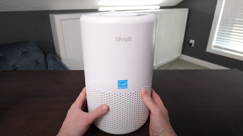 Man holding and reviewing personal smart air purifier at home
