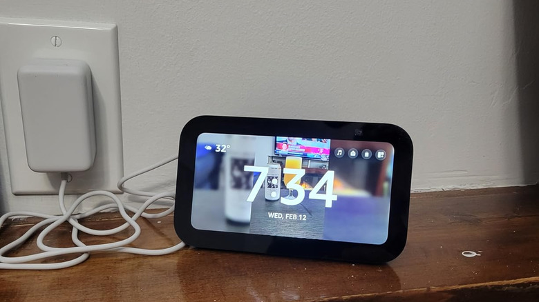 Charging Amazon tabletop smart tablet with time and background photo