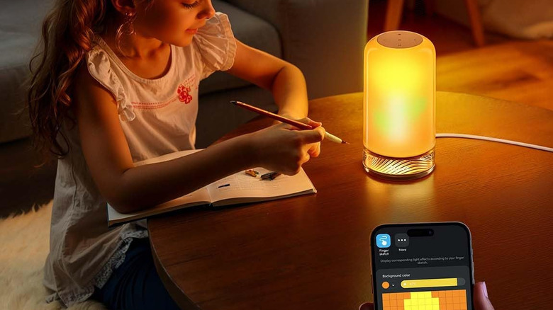Smart table lamp controlled via app beside young girl in dim living space
