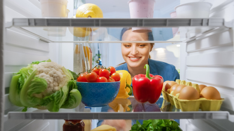 A woman looking inside a fridge.