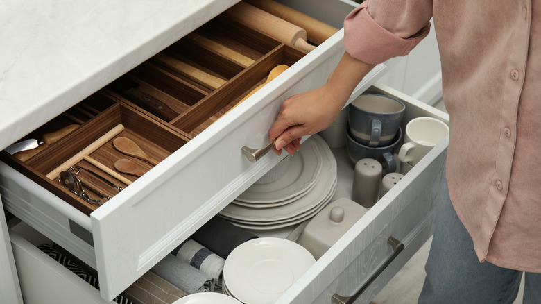 A woman opening drawers organized with dividers.