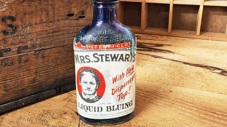 A vintage glass bottle of Mrs. Stewart's Bluing on a wooden table