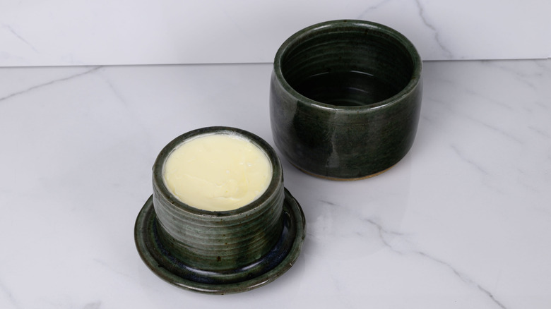 An open dark green butter bell on a marble counter