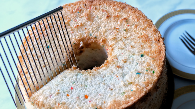 A cake breaker being used to slice into an angel food cake