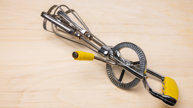 A yellow hand-crank egg beater