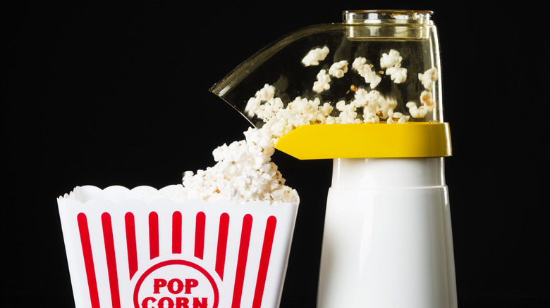 A hot air popcorn popper popping popcorn into a bucket