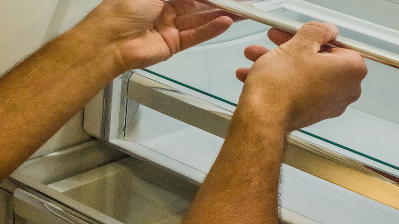 Hands grabbing a shelf in the fridge to adjust the spacing