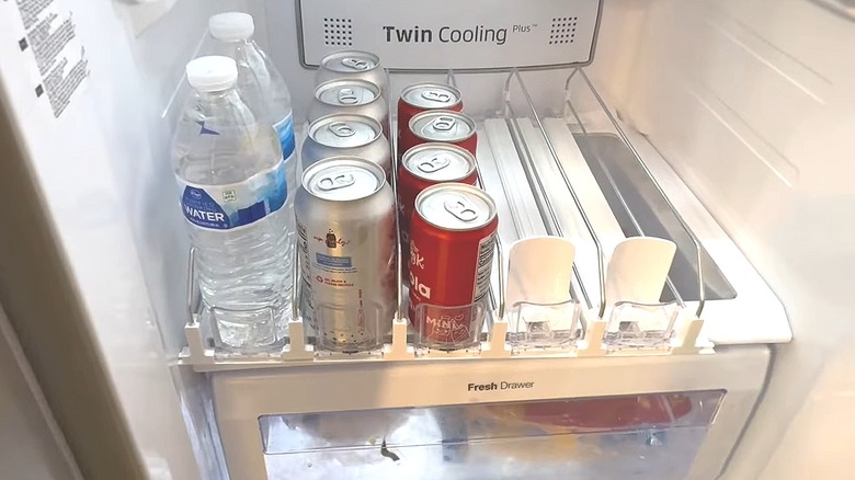 Drink dispenser in a refrigerator with bottled water and canned drinks in it
