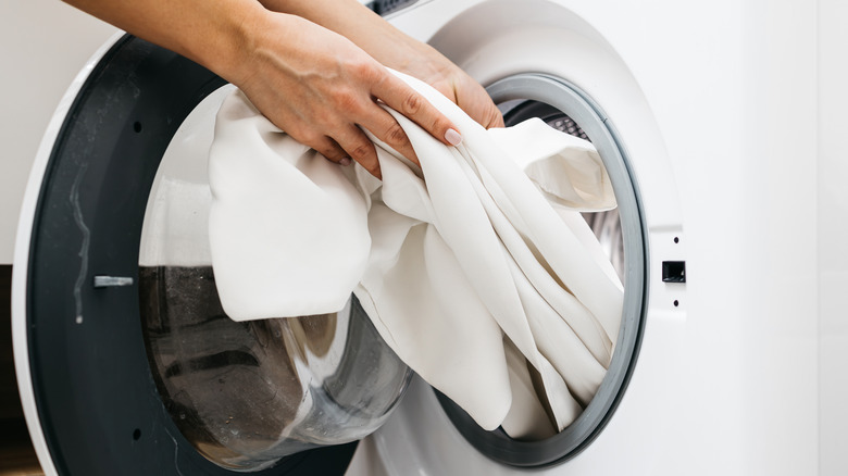person taking clothes out of a front loading dryer