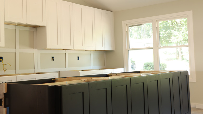 White upper cabinets, black lower cabinets in kitchen under construction