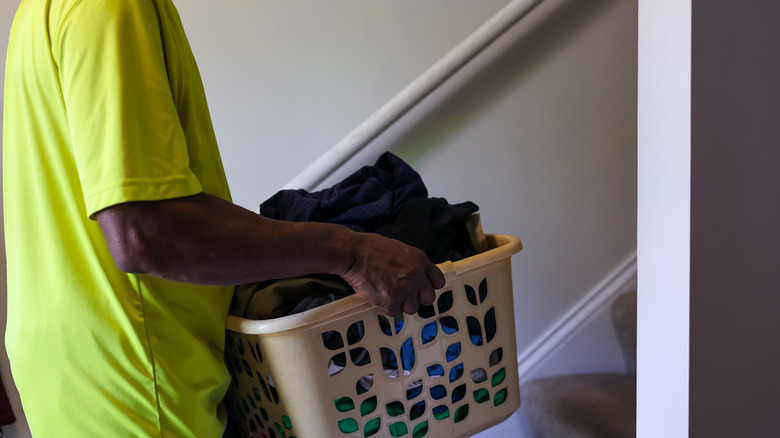 Person carrying a laundry basket up the stairs from the basement