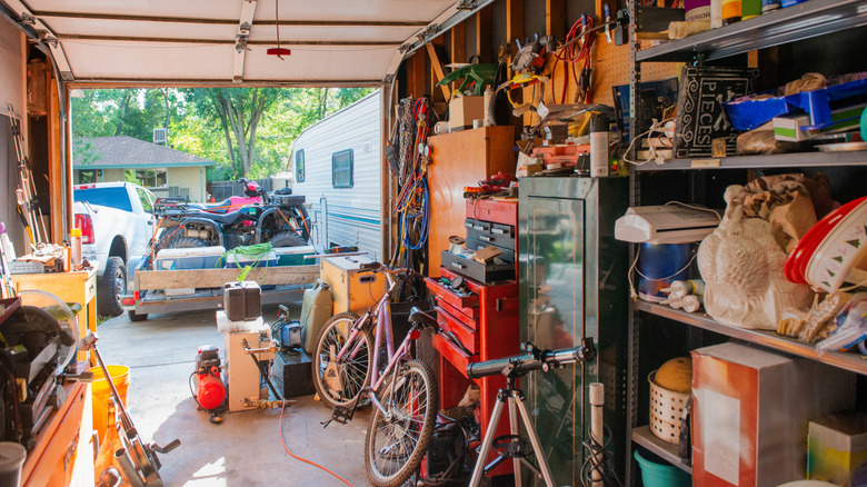 Cluttered garage with overflowing shelves and car parked outside