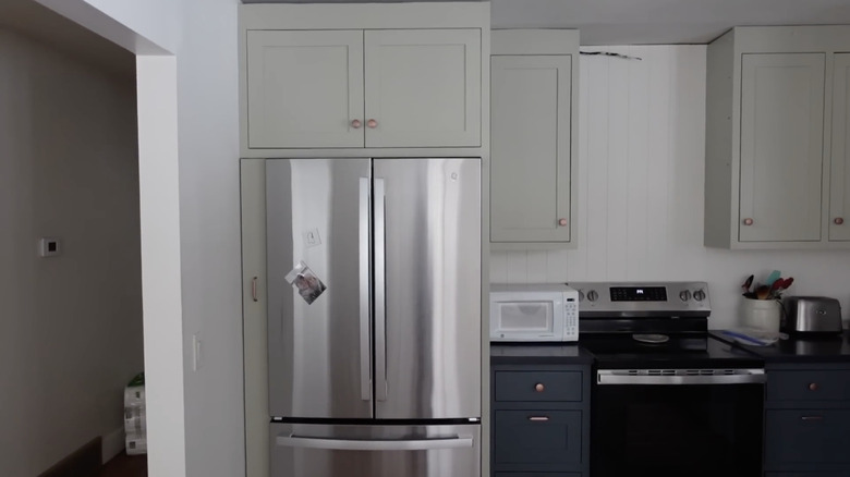 A slim, slide-out cabinet between a wall and refrigerator in a modern kitchen
