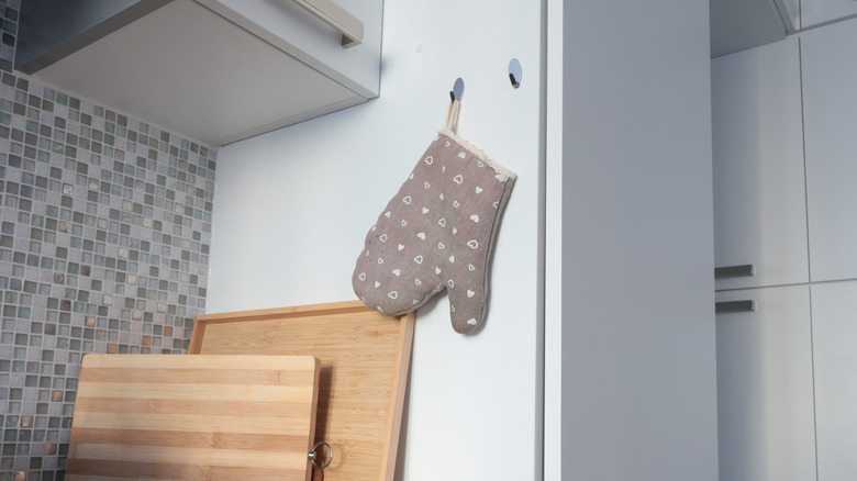 Pot holder hooks hanging from a hook on the side of a kitchen cabinet