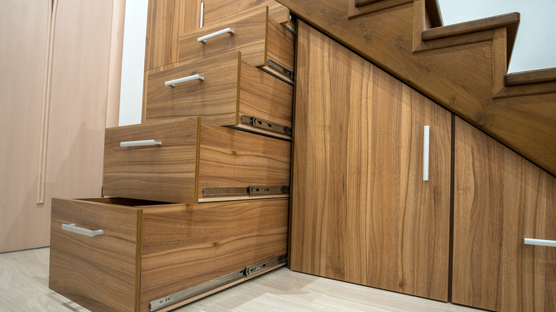Custom wooden under-stairs storage with cabinets and pull-out drawers