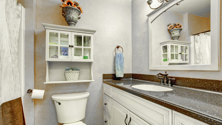 A small bathroom with a cabinet above the toilet