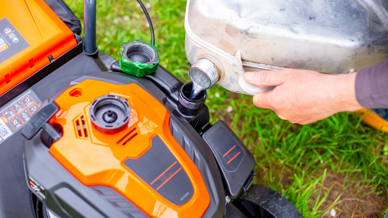 Gas being poured into lawn mower